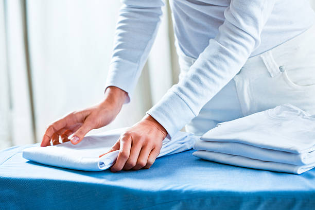 A person neatly folding freshly cleaned laundry on a table, showcasing professional wash and fold service efficiency.